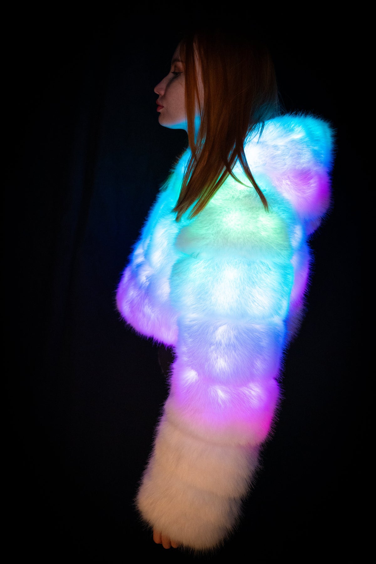 NEBUlux white LED faux-fur jacket glowing blue, green and pink, seen from the side.