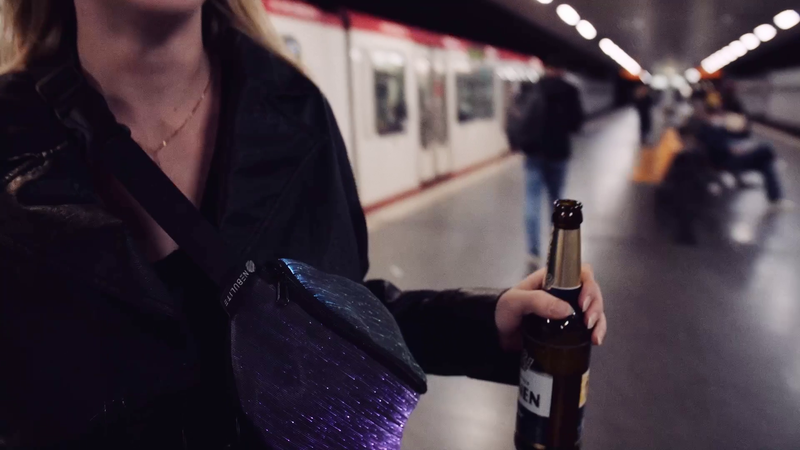 Video: NEBULITE Fanny Pack 4 in Wavy fabric worn crossbody on an underground platform, fibres lit purple and blue